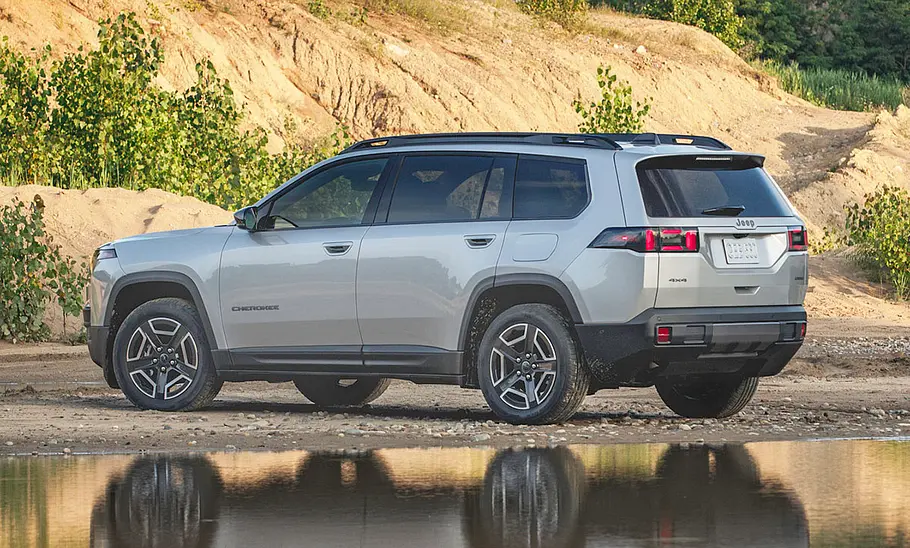 Der Jeep Cherokee steht in hügeligem Gelände, von hinten links fotografiert.