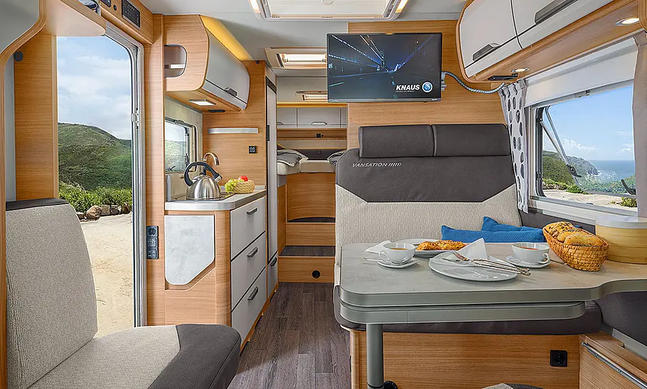 Knaus Van TI 650 MEG (2025) Die Innenaufnahme zeigt die Durchsicht durch den Wohnraum des Knaus Van TI 650 MEG (2025) mit Blick aus dem Cockpit in Richtung Heck.