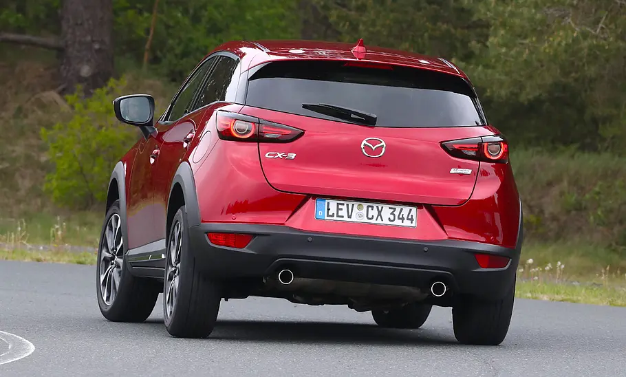 Mazda CX-3 (2018) Der Mazda CX-3 (2018) fährt eine Linkskurve, von hinten fotografiert.