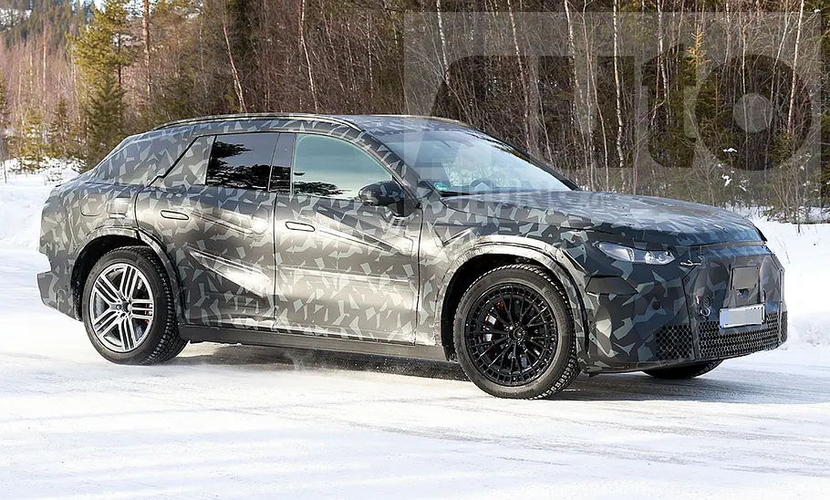 Das Mercedes-AMG SUV fährt als Erlkönig auf einer verschneiten Straße, von vorne rechts fotografiert.