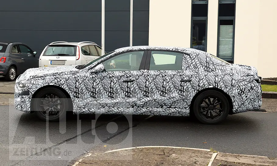 Die Mercedes E-Klasse EQ (2027) fährt als Erlkönig durch den öffentlichen Straßenverkehr, von links fotografiert.