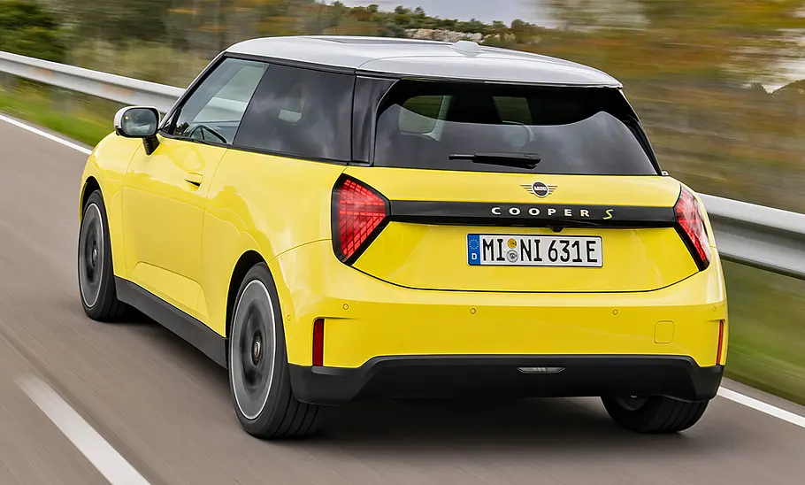 Mini Cooper SE (2024) in gelb, fahrend, von hinten links