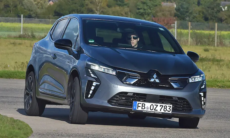 Der Mitsubishi Colt fährt durch eine Rechtskurve, von vorne fotografiert.