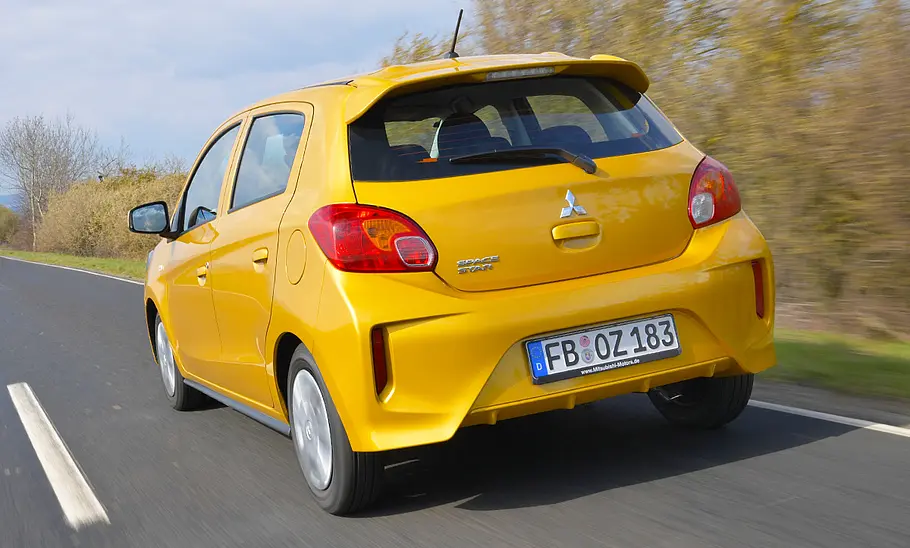 Der Mitsubishi Space Star (2020) fährt auf einer Straße geradeaus, von hinten links fotografiert.