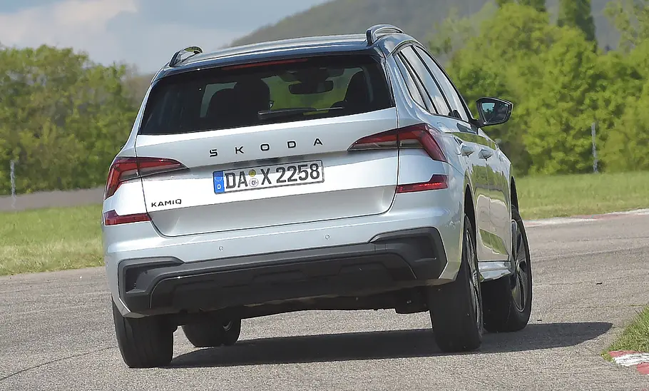 Der Skoda Kamiq fährt durch eine Rechtskurve, von hinten fotografiert.