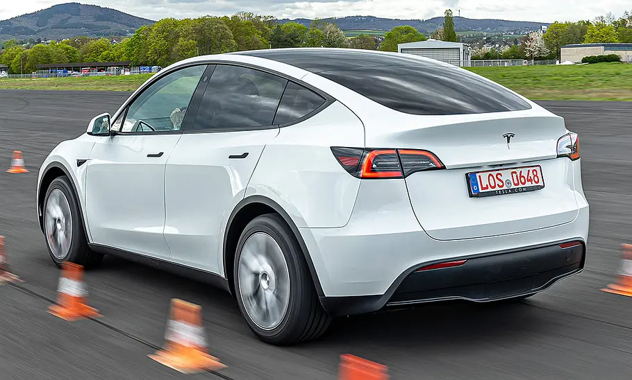 Weises Tesla Model Y Maximale Reichweite RWD fahrend, von schräg hinten