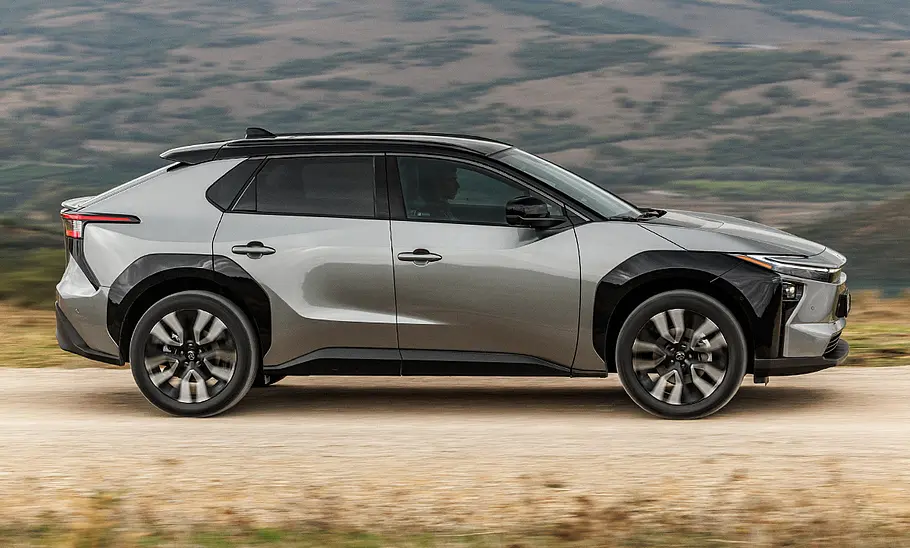 Das Toyota bZ4X Facelift fährt vor einem hügeligen Panorama, von rechts fotografiert.