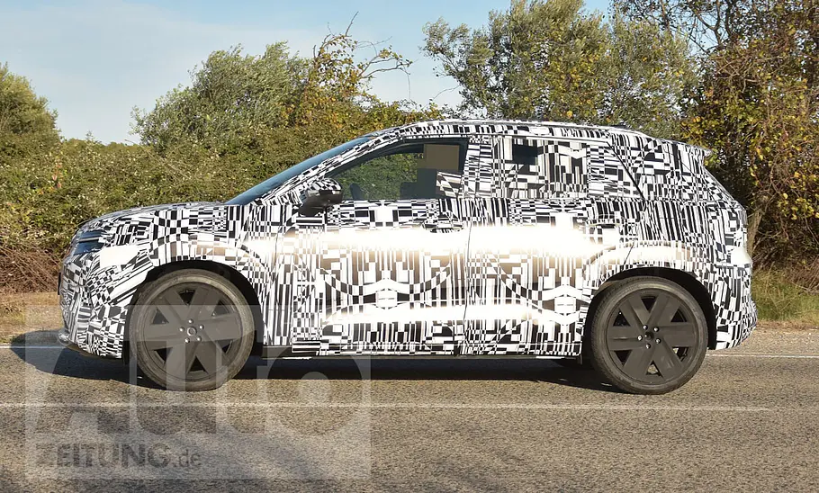 Der VW ID. Cross (2026) fährt als Erlkönig auf einer öffentlichen Straße, von links fotografiert.