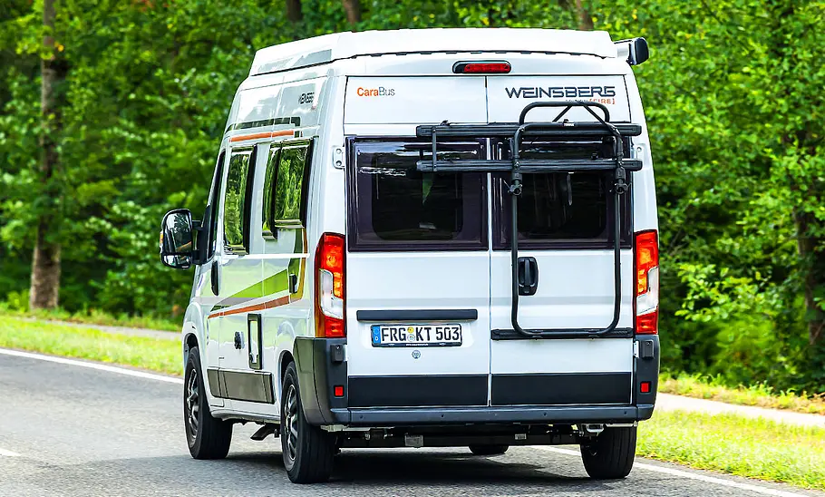Der Weinsberg CaraBus 540 MQ (2025) fahrend von schräg hinten links fotografiert.