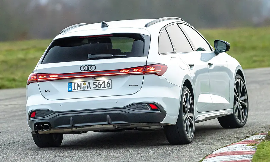 Der Audi A5 Avant fährt auf einer Rennstrecke durch eine Rechtskurve, von hinten rechts fotografiert.
