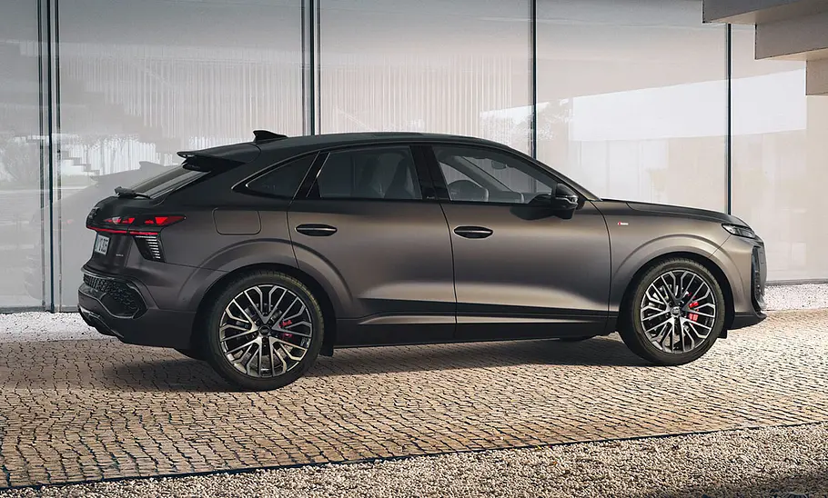 Audi Q3 Sportback 2025 stehend vor verglaster Hausfront, fotografiert von der Seite.