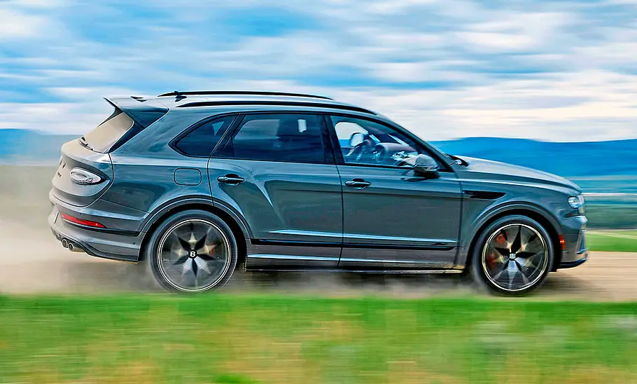 Bentley Bentayga Speed (2025) fährt auf einer staubigen Straße, Ansicht von der rechten Seite.