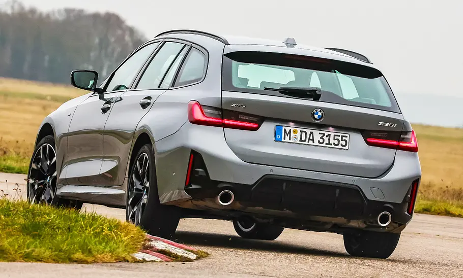 Blick von schräg hinten auf den fahrenden BMW 330i Touring.