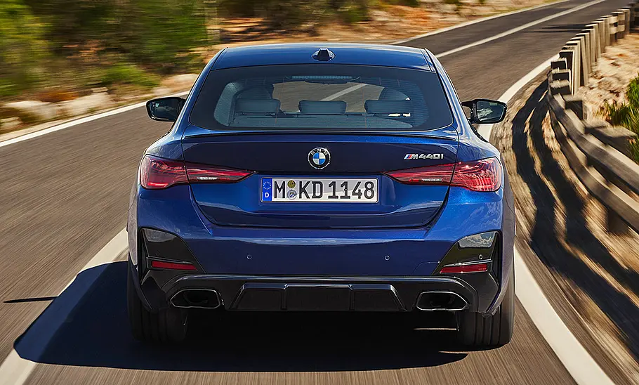 BMW M440i Gran Coupé Facelift (2024) Das BMW M440i Gran Coupé Facelift (2024) fährt auf einer Landstraße, von hinten fotografiert.