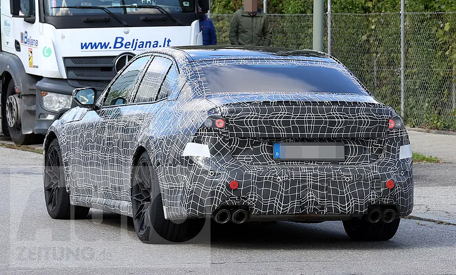 Der BMW M3 (2027) fährt als Erlkönig auf einer Straße, von hinten fotografiert.
