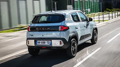 Die fahrdynamische Aufnahme zeigt den Dacia Spring (2026) von schräg hinten. - Foto: Dacia