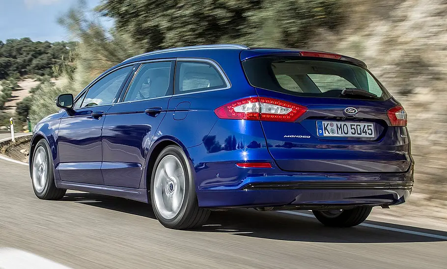 Ford Mondeo Turnier (2015) Der Ford Mondeo Turnier (2015) fährt auf einer Straße, von hinten links fotografiert.