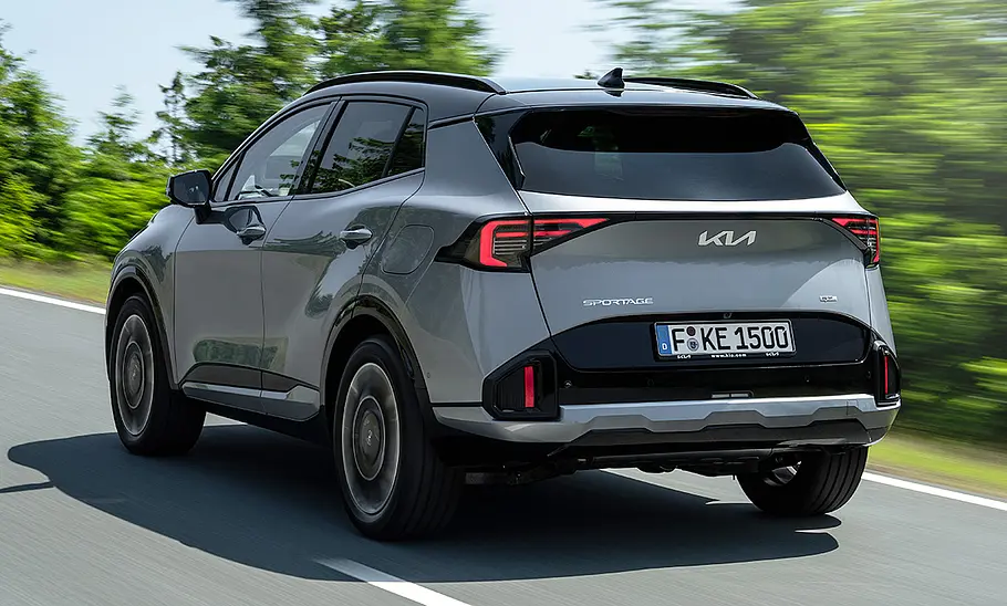 Kia Sportage (2025) Der Kia Sportage (2025) fährt auf einer Landstraße, von hinten links fotografiert.