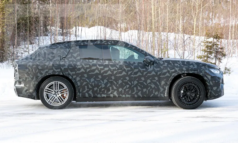 Das Mercedes-AMG SUV fährt als Erlkönig auf einer verschneiten Straße, von rechts fotografiert.