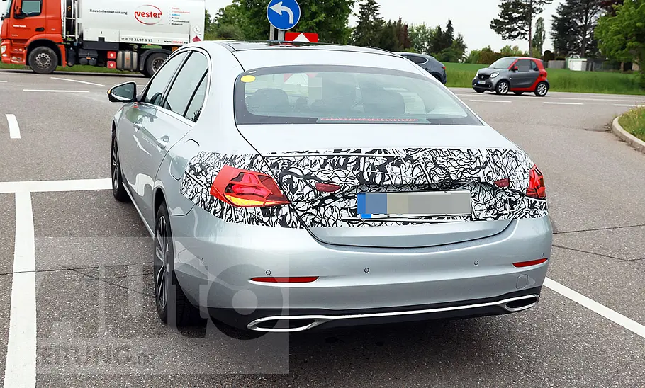Das Mercedes C-Klasse Facelift (2025) fährt als Erlkönig auf eine Kreuzung, von hinten fotografiert.