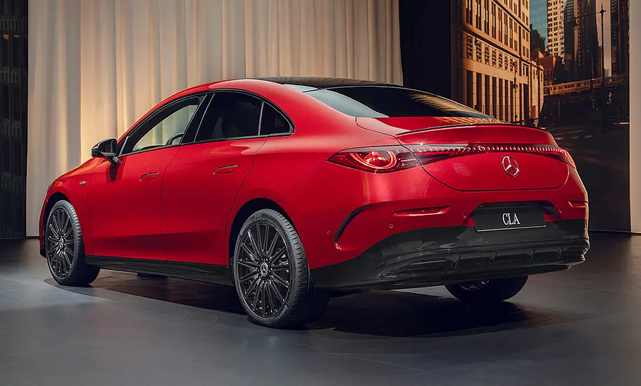 Mercedes CLA EQ (2025) Der Mercedes CLA EQ (2025) steht in Studioumgebung, von hinten links fotografiert.