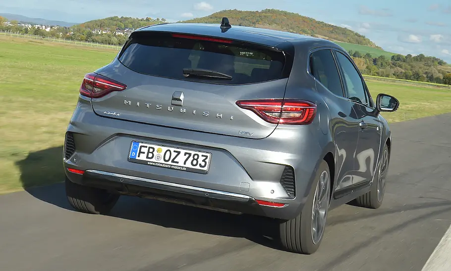Der Mitsubishi Colt Hybrid fährt geradeaus, von hinten rechts fotografiert.