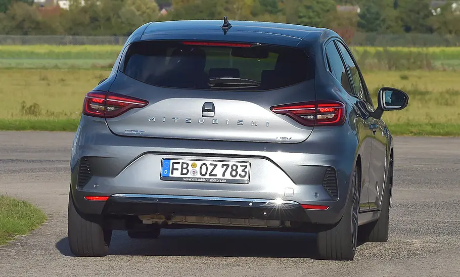 Der Mitsubishi Colt fährt durch eine Linkskurve, von hinten fotografiert.