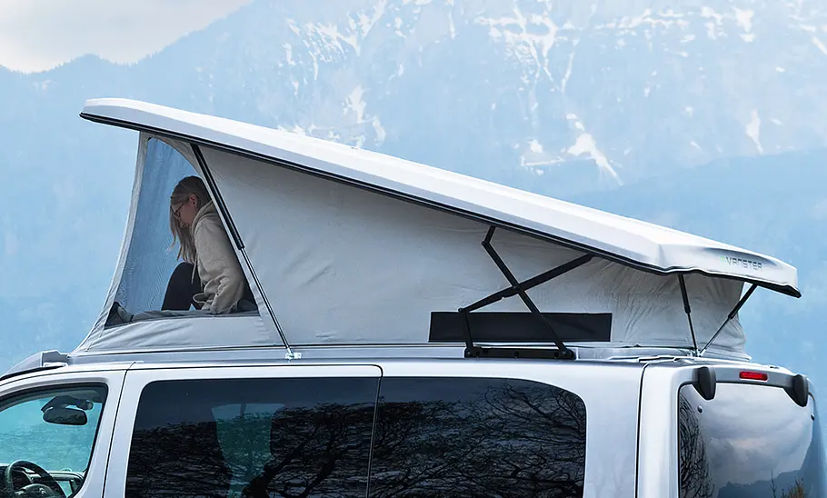 Pössl Vanster Das Bild zeigt das geöffnete Schlafdach des Pössl Vanster im Detail. Eine Person ist durch das Seitenfenster des Zeltbalgs zu sehen.