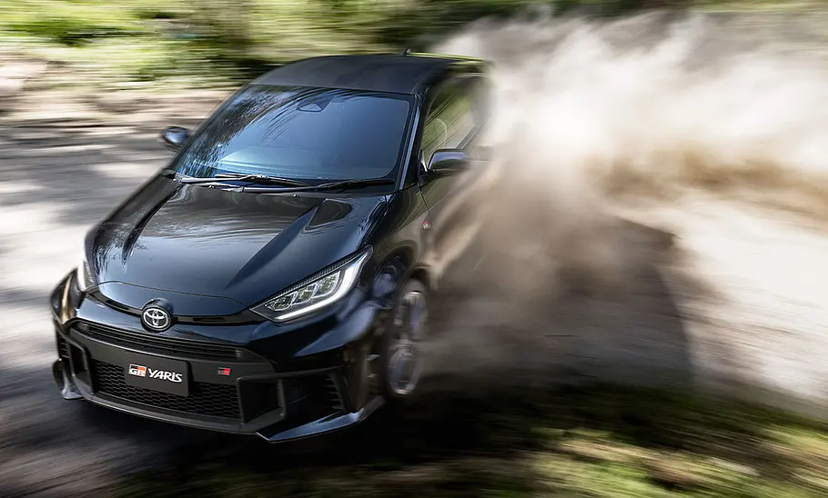 Toyota GR Yaris Facelift (2024) Das Toyota GR Yaris Facelift (2024) driftet auf losem Untergrund durch eine Linkskurve und wirbelt dabei viel Staub auf.