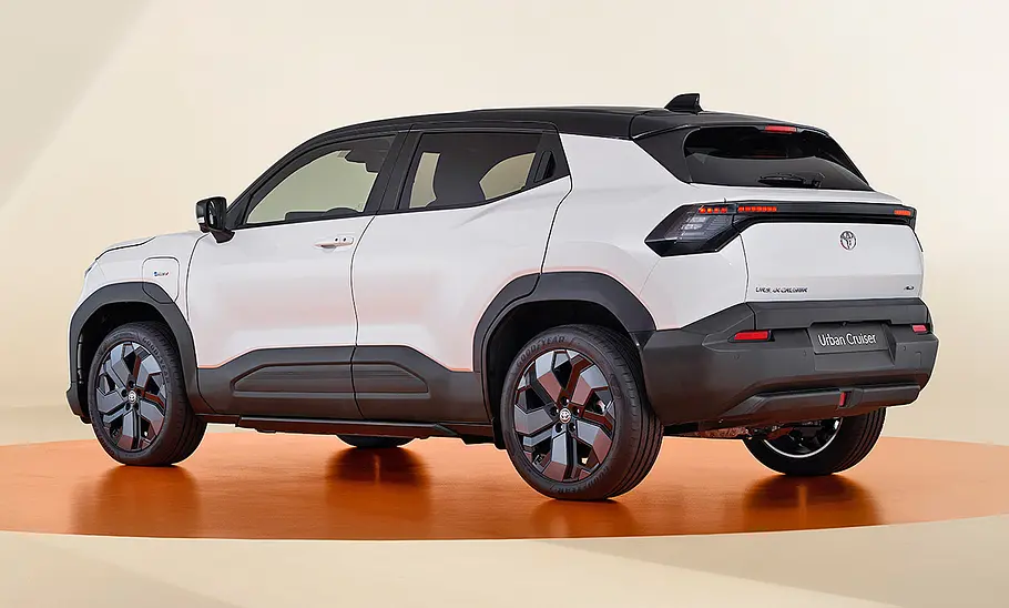 Toyota Urban Cruiser (2025) Toyota Urban Cruiser (2025) im Studio vor beigem Hintergrund, Ansicht von hinten links.