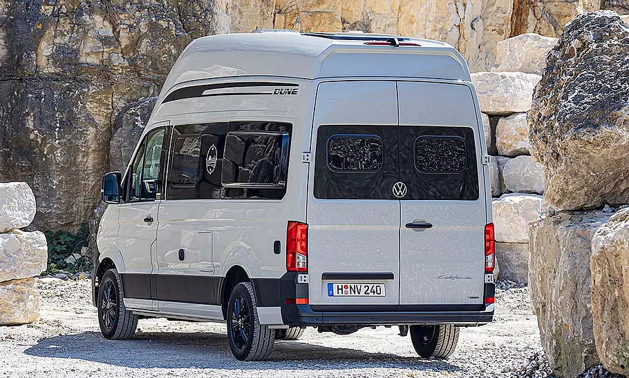 Die Außenaufnahme zeigt den VW Grand California Dune (2025) statisch von schräg hinten links.