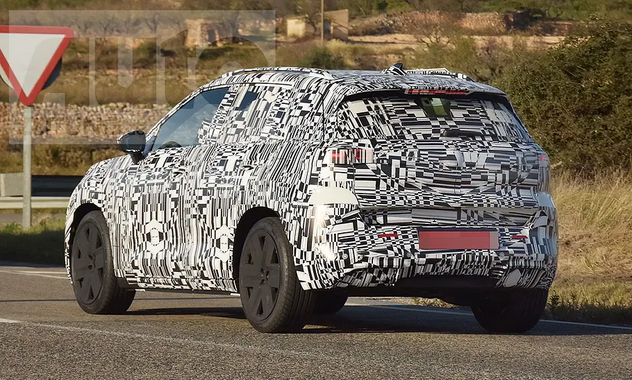 Der VW ID. Cross (2026) fährt als Erlkönig auf einer öffentlichen Straße, von hinten links fotografiert.