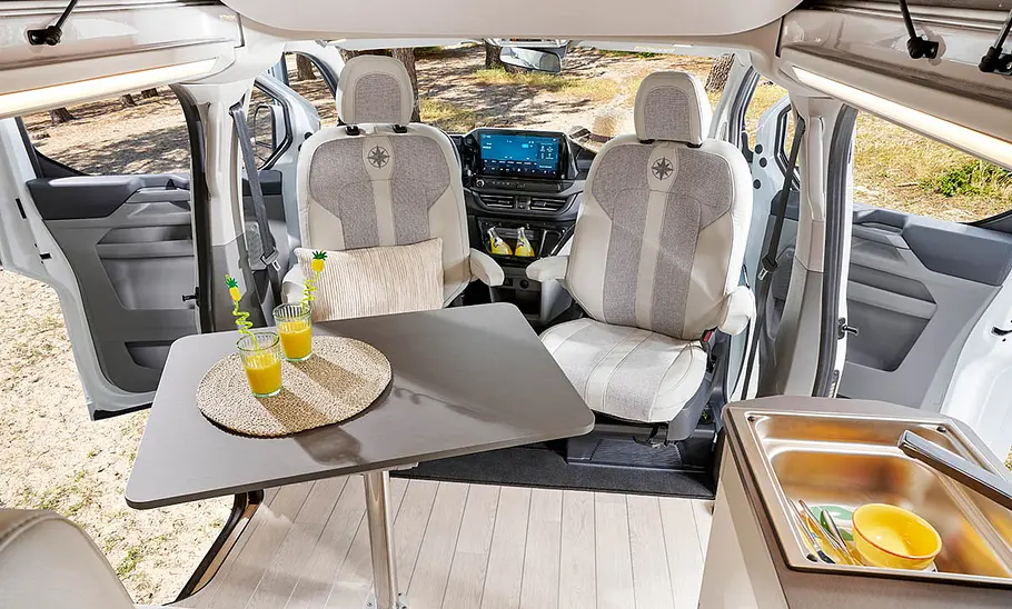 Blick auf den Tisch im Westfalia Kelsey (2025) vom Wohnraum aus, die Türen vorne sind geöffnet.