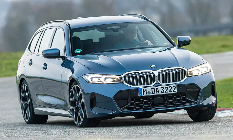 Der BMW 3er Touring fährt auf einer Rennstrecke durch eine Linkskurve, von vorne rechts fotografiert.