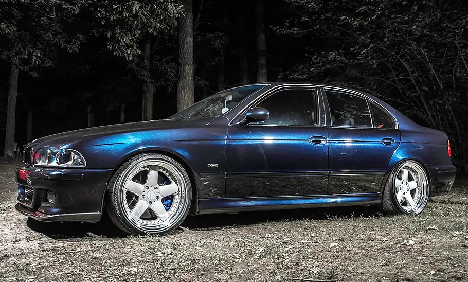 Getunter BMW 5er E39 mit Toyota-Motor im Wald, fotografiert von der Seite.