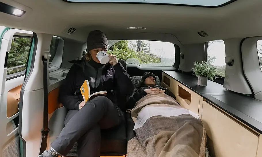 Peace Vans Buzz.Camper Peace Vans Buzz.Camper mit einer Liegefläche und einer Sitzgelegenheit daneben.