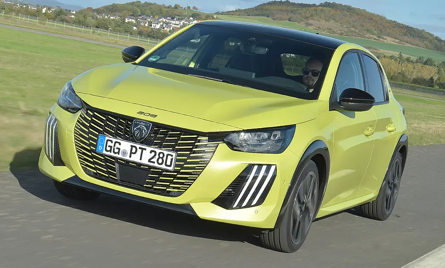 Der Peugeot 208 Hybrid fährt geradeaus, von vorne links fotografiert.