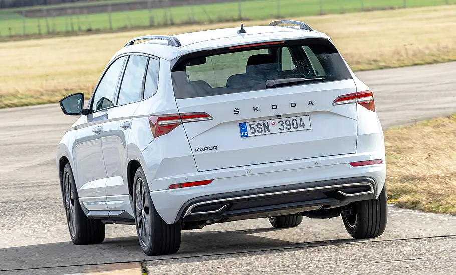 Der Skoda Karoq fährt durch eine Rechtskurve, von hinten fotografiert.