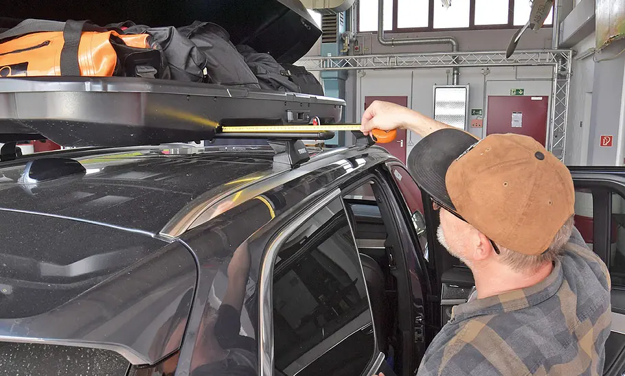 Thule Force 3 im Dachboxen-Test Ein Tester beim Messen der Position der Dachbox Thule Force 3, fotografiert von hinten.