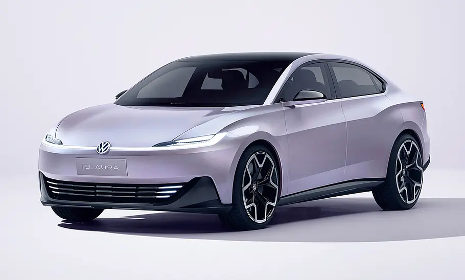 Der VW ID. Aura (2025) steht in Studioumgebung, von vorne links fotografiert.