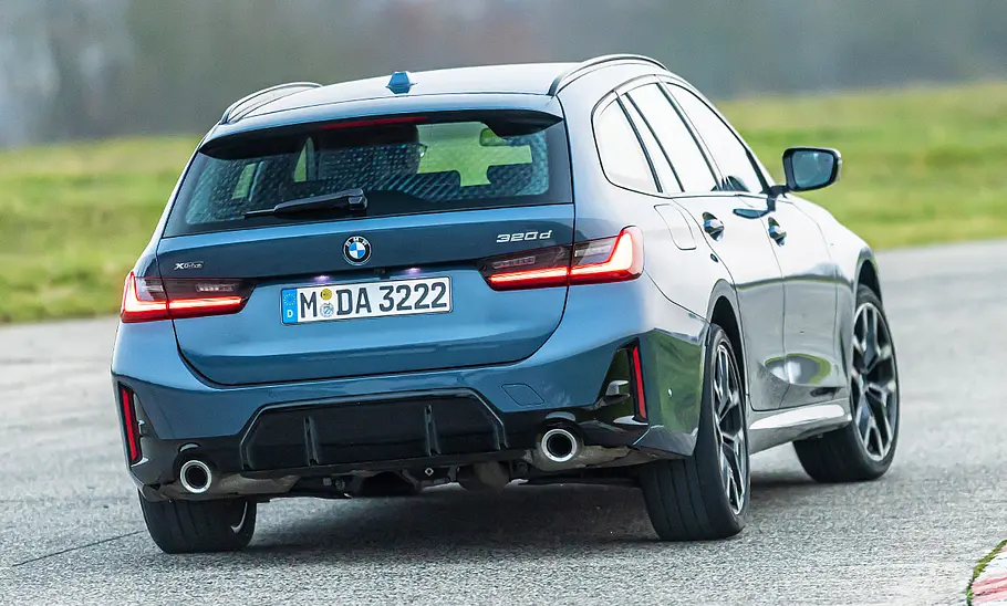 Der BMW 3er Touring fährt auf einer Rennstrecke durch eine Rechtskurve, von hinten rechts fotografiert.