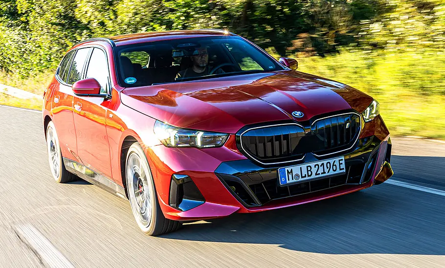 Der BMW i5 Touring auf der Landstraße, von schräg vorne fotografiert.