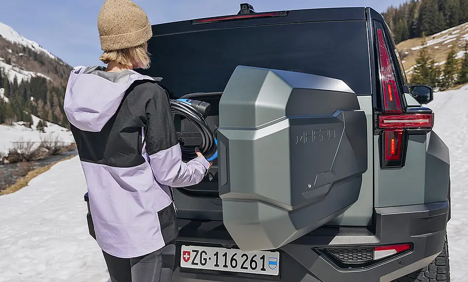 Dongfeng MHero 1 (2024) Dongfeng MHero 1 (2024) statisch, im Schnee von hinten, Person verstaut Ladekabel im Heck