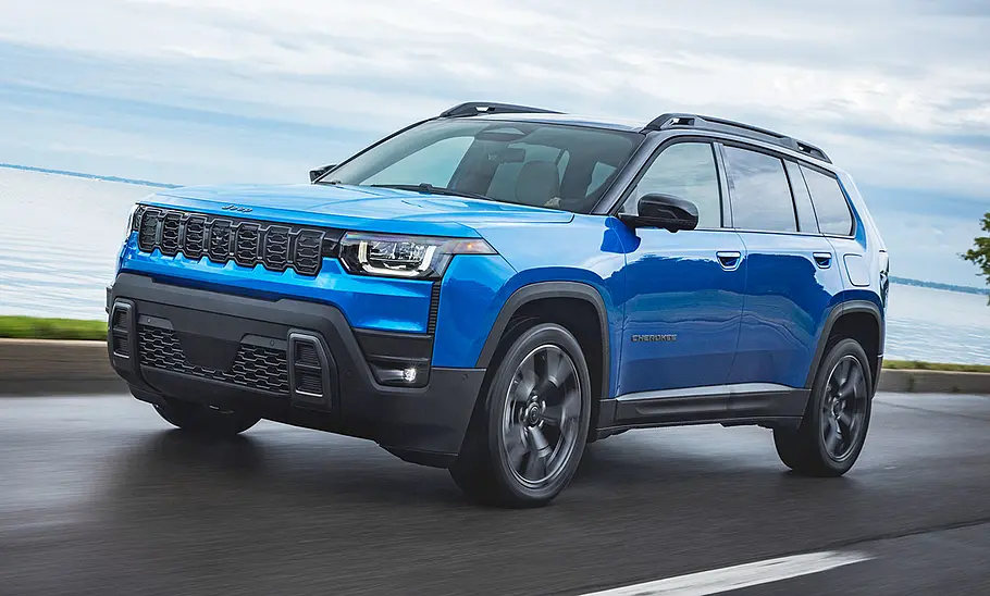 Der Jeep Cherokee fährt eine Küstenstraße entlang, von vorne links fotografiert.