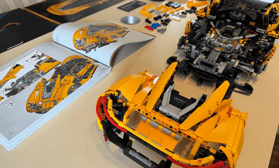 Das Bild zeigt den Lego Technic McLaren P1 während des Aufbaus. Neben dem aufgebauten Heck des Modells liegt die Bauanleitung.