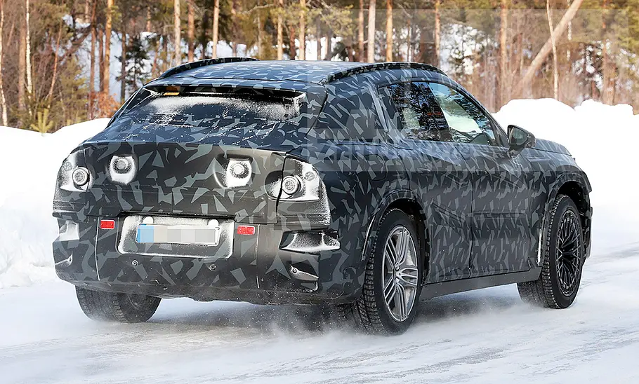 Das Mercedes-AMG SUV fährt als Erlkönig auf einer verschneiten Straße, von hinten fotografiert.