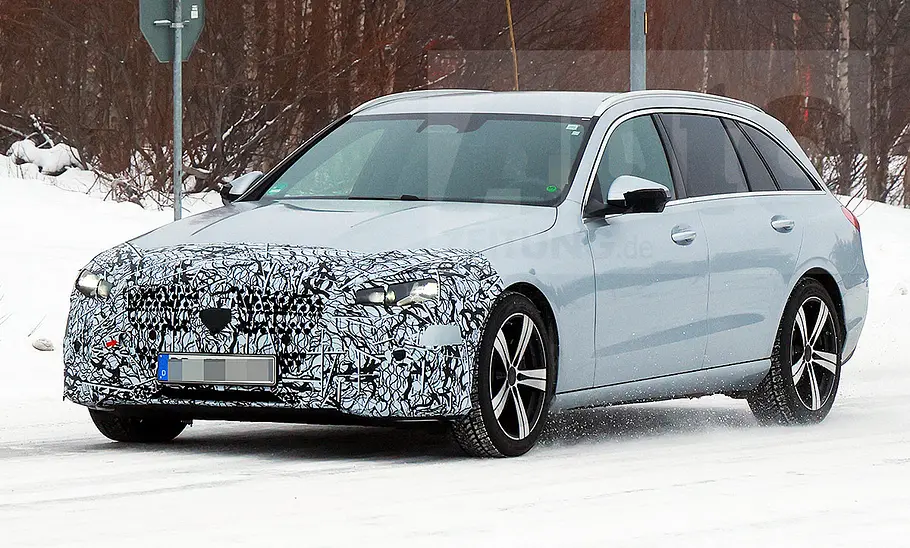 Das Mercedes C-Klasse T-Modell Facelift (2025) fährt als Erlkönig auf einer verschneiten Straße, von vorne links fotografiert.