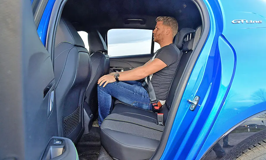 Peugeot 208 (2019) Peugeot 208 (2019) Rücksitzbank, Ansicht durch die geöffnete hintere linke Tür, eine Person sitzt hinter dem Beifahrersitz.