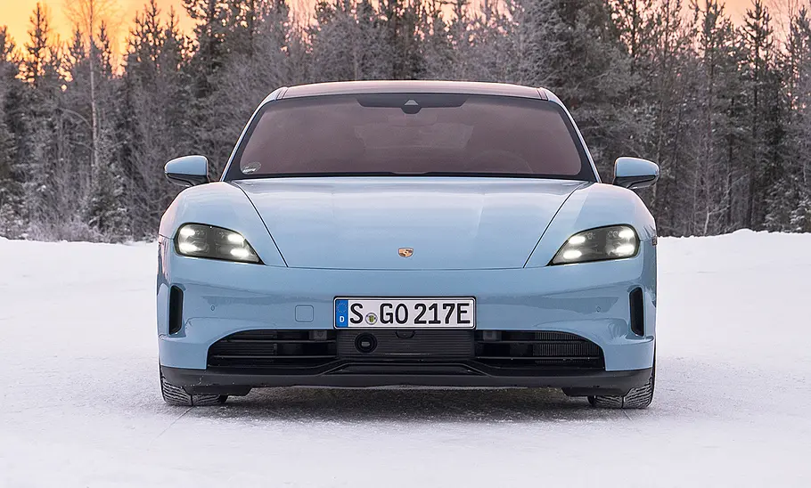 Das Porsche Taycan 4 Facelift (2025) steht im Schnee, statisch von vorne fotografiert.