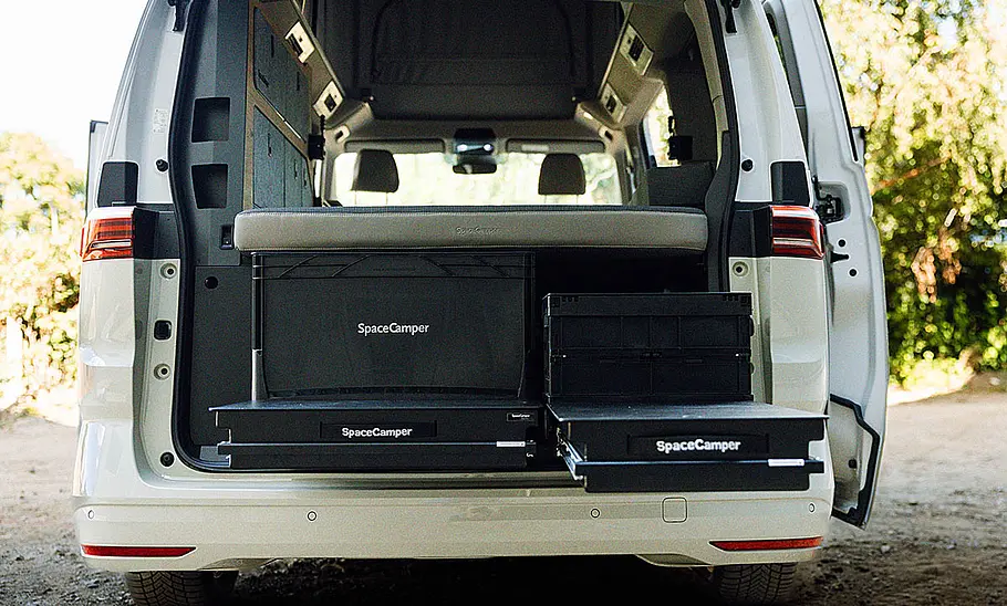 Spacecamper Classic+ Multivan (2025) Die Außenaufnahme zeigt ausgezogene Schubladen im geöffneten Heck des Spacecamper Classic+ Multivan.